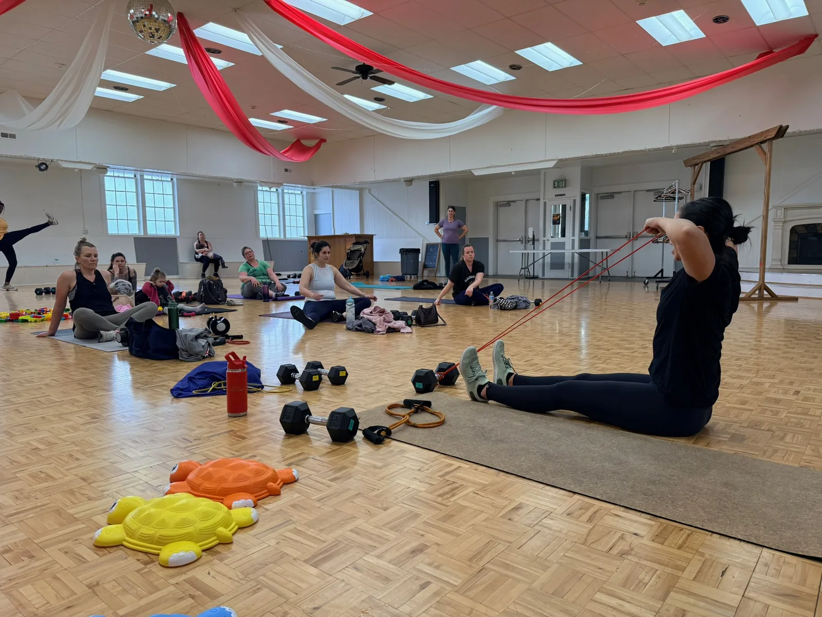Coach demonstrating a banded row while the class watches at an indoor session