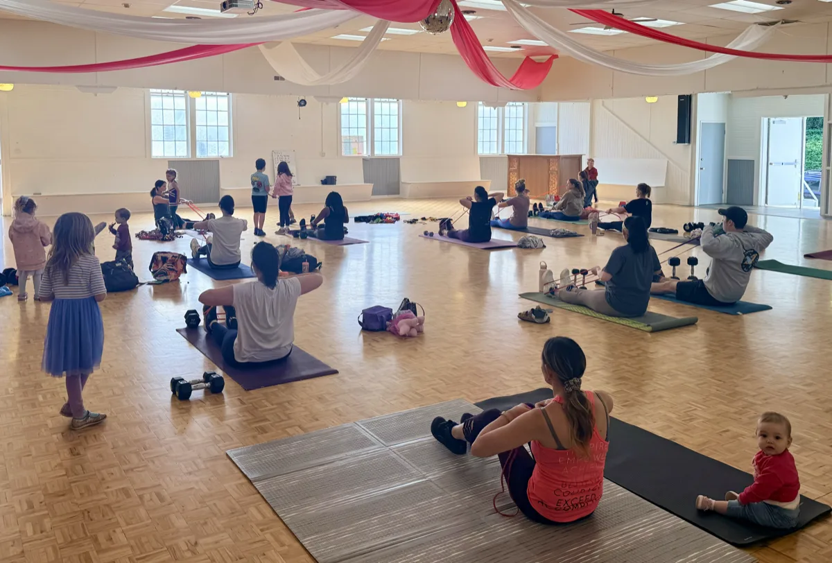 Members pressing dumbbells overhead together at an outdoor class